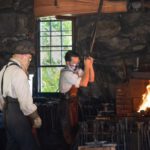 Blacksmithing - a couple of men working in a brick room with a fire